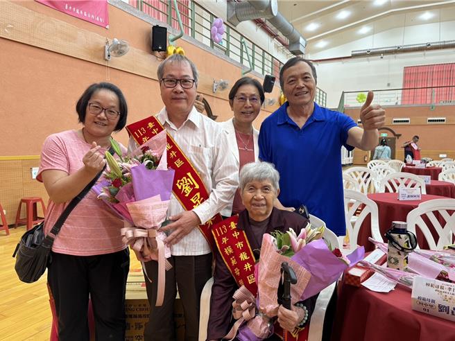 台中市龙井区公所27日上午皆举办模范母亲与孝行楷模表扬，92岁的刘黄素贞（前中）与丈夫共渡生活风霜，辛苦拉拔3个孩子长大，今日获奖，开心之情溢于言表。（潘虹恩摄）