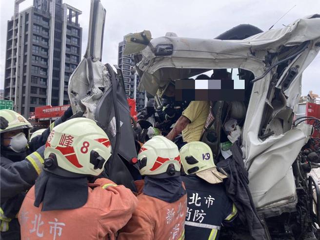 国1汐止交流道货柜车翻覆，驾驶受困车内。（新北市消防局提供）