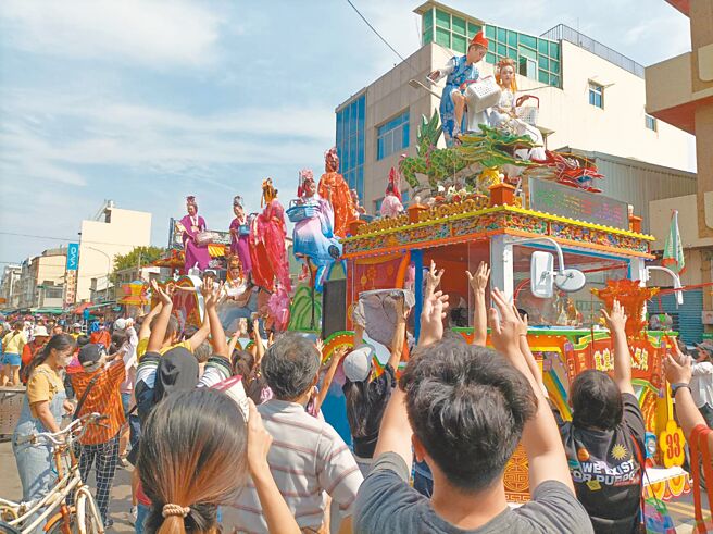 雲林北港迎媽祖的真人藝閣所到之處引起圍觀，民眾紛紛伸長手，等著接藝閣上的仙女、仙人灑下糖果。（周麗蘭攝）