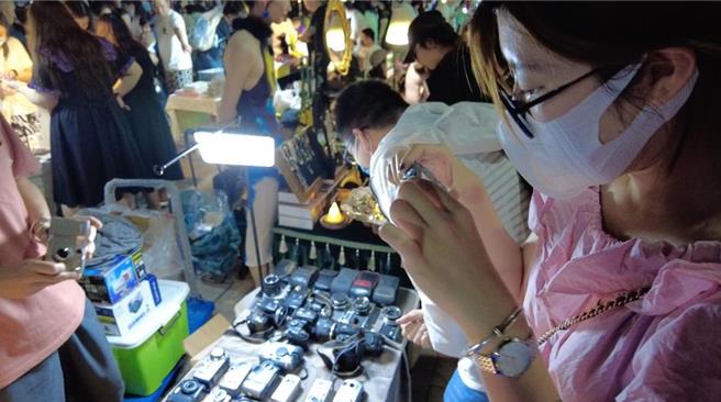 一位顾客在北京潘家园二手相机摊贩试用CCD相机。（摘自中新社）