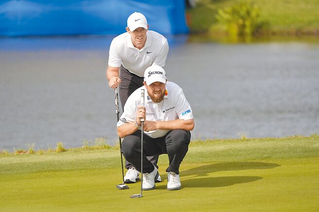 麥克羅伊站在勞瑞身後一起觀察果嶺狀態。（美聯社）