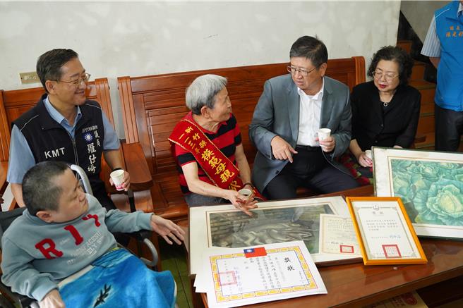 新竹县关西镇陈邱贤妹（左三）照顾玻璃娃娃女儿，不辞辛劳一路陪伴女儿至大学毕业，获得今年新竹县模范母亲给力妈妈代表，县长杨文科（左四）亲自带着匾额祝贺。（新竹县府提供／邱立雅竹县传真）