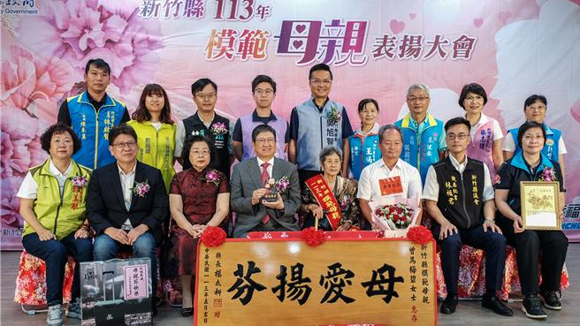 新竹縣113年模範母親表揚大會，竹北市96歲曾馬梅碧是年紀最大模範母親（右四），縣長楊文科（左四）頒贈「母愛揚芬」匾額及母親節禮物。（羅浚濱攝）