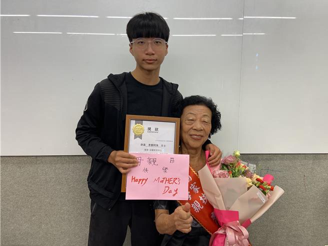今日受表扬的李郑阿珠（右）总是笑咪咪的面对大家，其孙子李家杰（左）送阿嬷亲手做的卡片。（吴佩蓉摄）