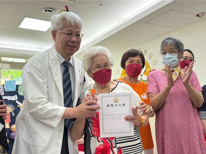 台中醫院10日替日照中心與護理之家長輩們提前慶祝母親節，春鸞阿嬤（左二）等5位媽媽打扮妖嬌亮麗走秀展現青春活力，台中醫院院長黃元德贈送代表永恆母愛的「永生花之暉」。（潘虹恩攝）
