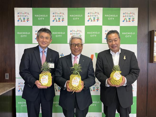 八王子市长初宿和夫(左)、八王子台湾交流协会理事长黑须隆一(中)、八王子市教育委员会教育长安间英潮(右)与高雄凤梨合影。（图／高雄市农业局）