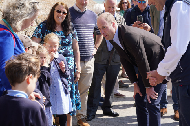 英國威廉王子10日訪問康瓦耳夕利群島聖瑪麗港，與當地學童互動。（路透）