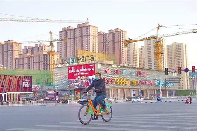 为适应住房市场的供求关系变化，全大陆已有多地调整或取消限购政策。图为山西太原市民从建案前经过。（中新社）