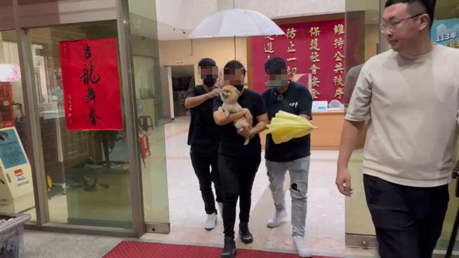 大女兒抱著母親的愛犬不發一語的離開分局。（翻攝畫面）
