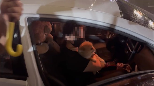 大女兒抱著母親的愛犬不發一語的離開分局。（翻攝畫面）