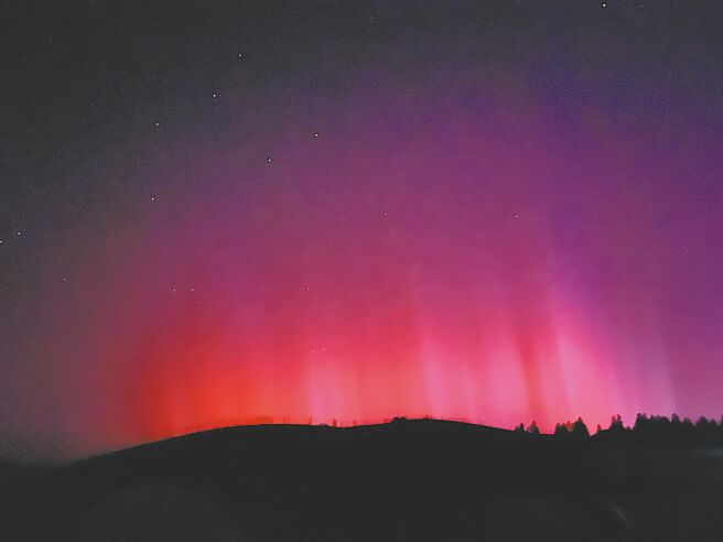 中央气象署10日发布「地球磁暴」示警，中美等世界多国也相继发布磁暴警告，全球多地出现极光，图为11日在新疆乌鲁木齐出现的极光。（新华社）