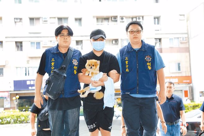 涉嫌新北市三重区祖孙三代3尸命案的张姓男子（中），12日遭警方逮捕，带回三重警分局时，他怀中仍紧抱爱犬。（张铠乙摄）