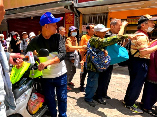 排队领爱心麵包民眾(绿衣者)怒吼「不要插队」，场面火爆。(吴振煌拍摄)