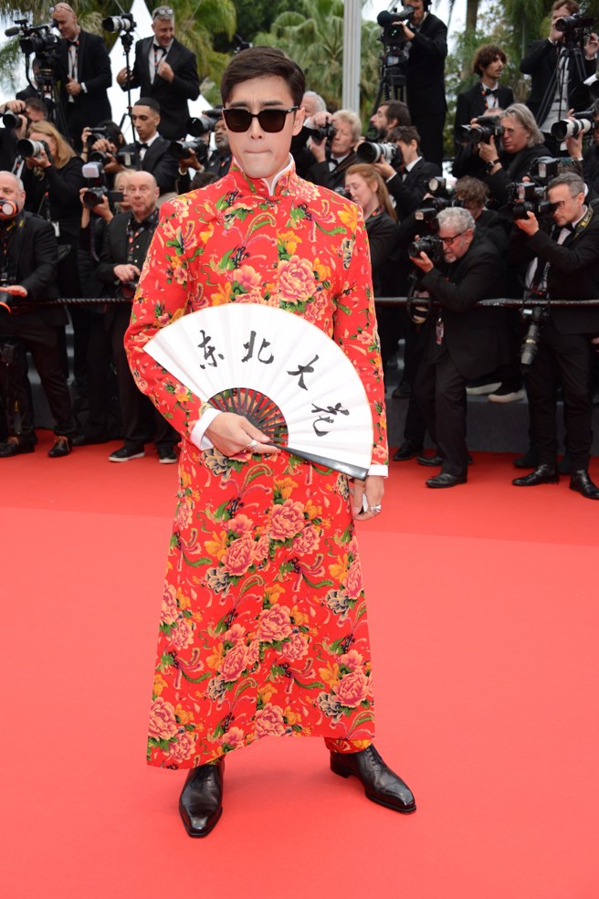 美混血網紅李美越穿著大紅花唐裝，手裡拿著寫有「東北大花」及「征服世界」的扇子。（圖／shutterstock／達志）