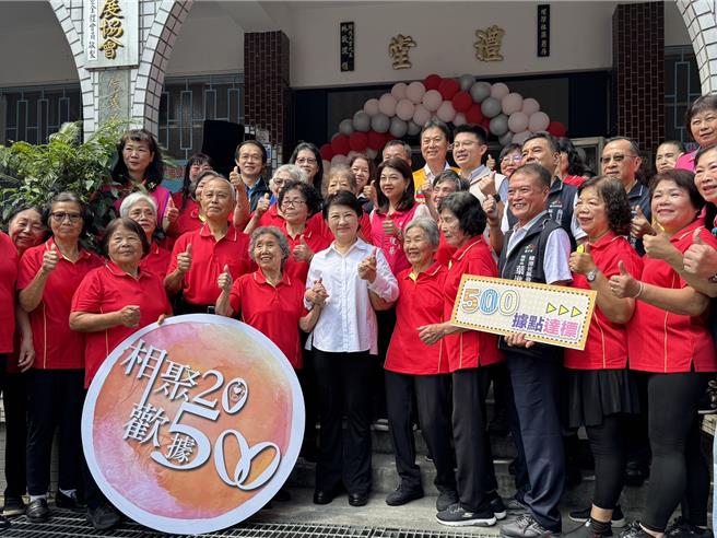 适逢台中市推动关怀据点服务20年并达成500站点里程碑，台中市长卢秀燕（左五）17日赴乌日区螺潭社区为关怀据点揭牌，开心牵起89岁与86岁2位奶奶合影。（潘虹恩摄）
