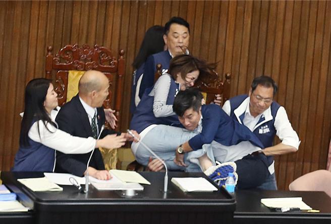 立法院17日院会表决大战一触即发，民进党立委锺佳滨（右二）翻上桌衝向主席台，挡在院长韩国瑜（左二）前的国民党立委陈菁徽（中右）前被锺一把抱住，2人双双跌落桌下。（姚志平摄）