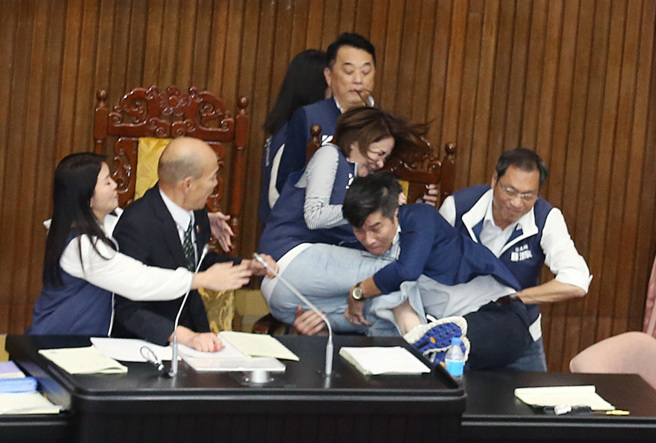 立法院17日院会表决大战一触即发，民进党立委锺佳滨（右二）翻上桌衝向主席台，挡在院长韩国瑜（左二）前的国民党立委陈菁徽（中右）前被锺一把抱住，2人双双跌落桌下。（姚志平摄）