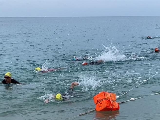 澎湖鐵人三項開賽，6國400名選手19日拂曉挑戰113公里，報名游泳接力卻沒有雙臂的林育夙（中間紅白泳帽），奮力踢水完成游泳階段，也達到自我期許目標。（許逸民攝）