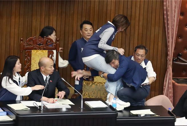 立法院17日院會表決時，民進黨立委鍾佳濱（右二）翻上桌衝向主席台，擋在院長韓國瑜（左二）前的國民黨立委陳菁徽（中右）被鍾一把抱住，2人雙雙跌落桌下。（資料照，姚志平攝）