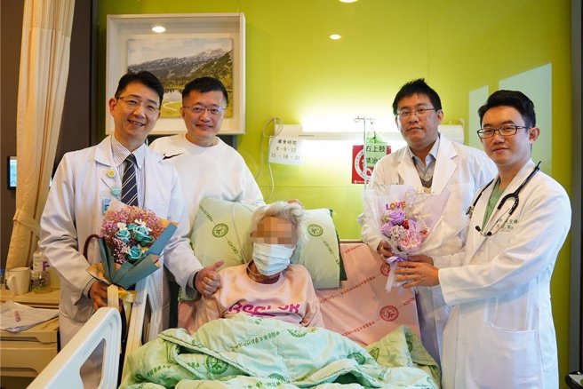 罹患乳癌的86岁林姓阿嬷（中）心臟衰竭送中医大新竹附医救回一命，与内科副院长刘俊廷（左）、其子林玉龙（左二）加护病房吴宣锋医师（右）、血液肿瘤科医师蔡明宏（右二）合影。（中医大新竹附医提供／罗浚滨新竹传真）