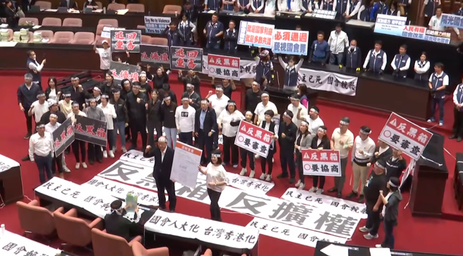 民进党立委进入议场，铺满布条，高呼「民主已死」、「反黑箱」、「退回重审」。(截自中时新闻网)
