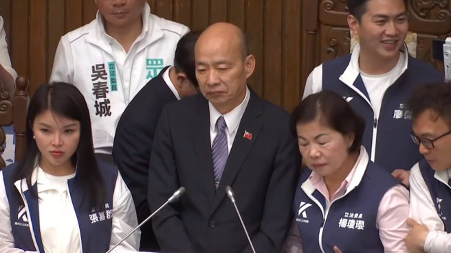 立法院长韩国瑜在蓝委保护下登上主席台主持议事，但台下民进党立委仍不断高呼口号，与台上国民党立委比大声。(截自中时新闻网)