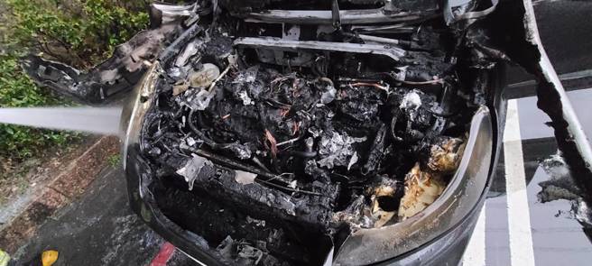 黑色轎車駕駛發現車輛故障，才剛停好車就起火燃燒，所幸消防隊即刻到場灌救。（翻攝畫面）