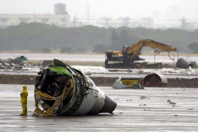 2000年11月4日，台北中正國際機場跑道上，保安人員在新加坡航空公司SQ006航班殘骸前，一具損壞的發動機前。（美聯社）