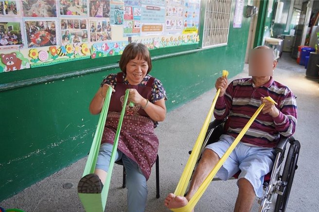 刘月华（左）陪伴长辈运动，看见长辈们日渐进步，让她更有服务动力。（屏东县政府提供／罗琦文屏东传真）