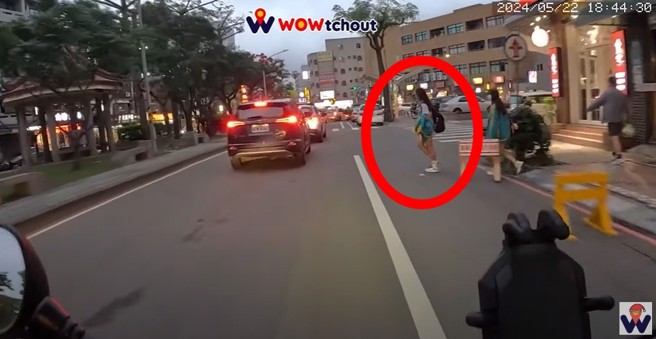 女學生違規過馬路時，完全沒有看來車，是聽到喇叭聲才抬頭，但是並沒有停下的動作，持續違規穿越馬路。（翻攝WoWtchout - 地圖型行車影像分享平台）