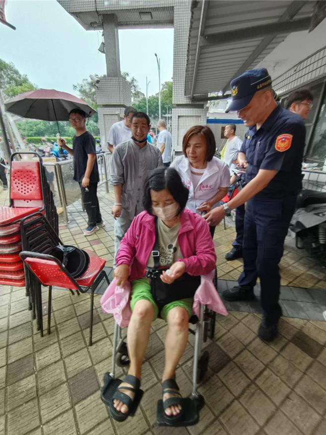 妇人去投票时不慎绊倒，膝盖受伤，黄露慧上前慰问，帮推轮椅。（廖素慧摄）