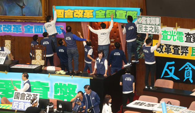 國會改革相關法案將拼在28日立法院院會三讀，一早議場開門後，國民黨立委們及民進黨立委先後進入議場，雙方用布條標語布置場內，展現各自的訴求。（陳君瑋攝）