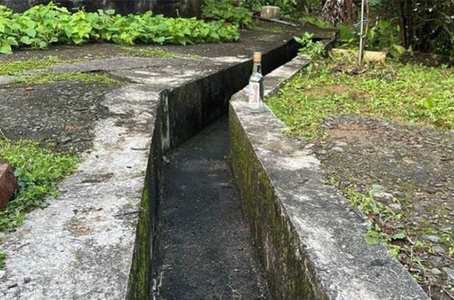 基隆市中山区通仁街昨日1名47岁的王男倒卧水沟中身亡，现场留有未开封高粱酒瓶，检警初步排除他杀。死因今日检方将相验厘清。（翻摄画面／徐佑升基隆传真）