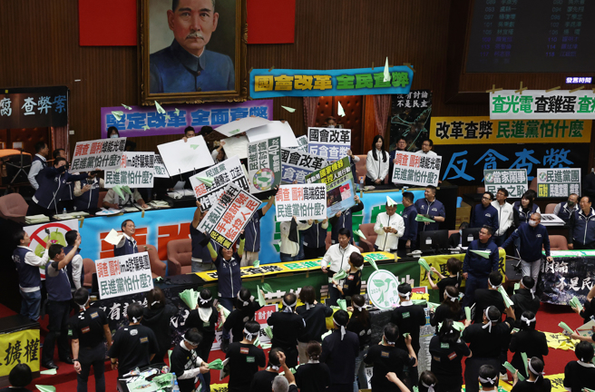 立法院院會28日續審國會改革相關法案，在「立法院職權行使法修正草案」全數二讀通過後，民進黨立委們在議場射起紙飛機，而國民黨立委們見狀立刻用手板遮擋。（劉宗龍攝）