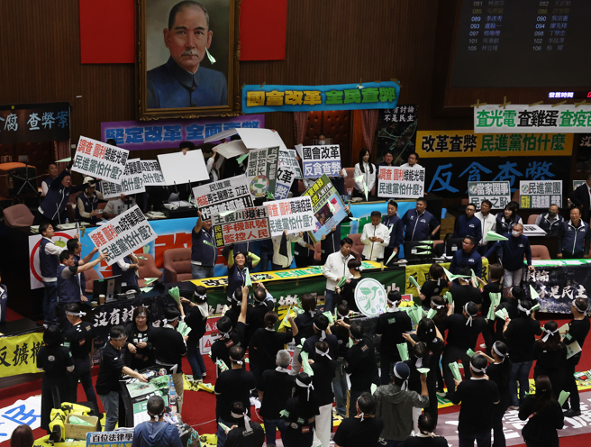 立法院院會28日續審國會改革相關法案，在「立法院職權行使法修正草案」全數二讀通過後，民進黨立委們在議場射起紙飛機，而國民黨立委們見狀立刻用手板遮擋。（劉宗龍攝）