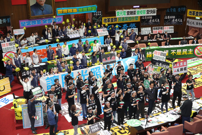 立法院院會28日續審國會改革相關法案，傍晚時全案三讀包裹表決，國民黨、民眾黨以人數優勢完成三讀程序，立法院長韓國瑜在三讀通過後敲槌，國民黨立委手持太陽造型氣球高喊支持，民進黨立委們則在台下比倒讚抗議。（黃世麒攝）