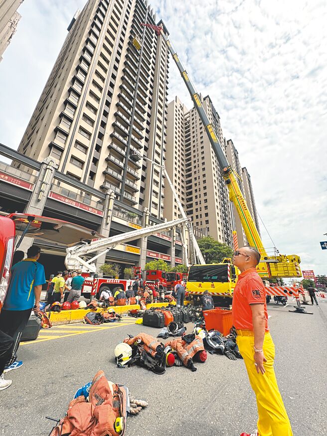 新竹市晴空匯大楼26日深夜发生火警引发浓烟，启德重机董事长胡汉龑（前）出动可升降78公尺、27楼高的大型吊车协助居民撤离。（陈育贤摄）