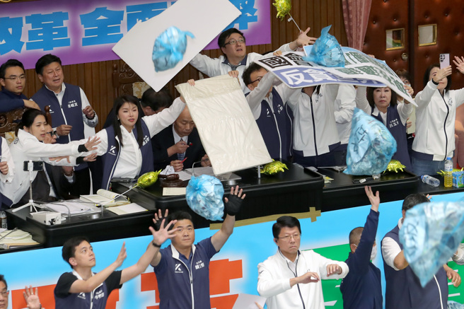 立法院院會28日續審國會改革相關法案，傍晚時全案三讀包裹表決，進入三讀程序時，民進黨立委將寫上「垃圾」字樣的藍色塑膠袋丟上主席台抗議，國民黨立委們舉起牌子阻擋。（資料照，黃世麒攝）