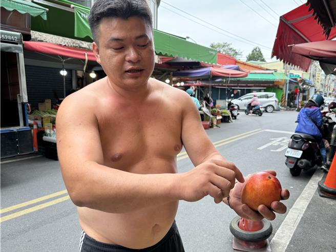 水果行簡老闆指出，其實果蠅叮過的芒果，肉眼仔細看可以看到小洞。（吳佩蓉攝）