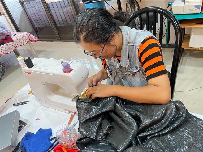 黄怡芳正缝制客人订做的布袋戏服装。（翻摄照片／洪靖宜高雄传真）