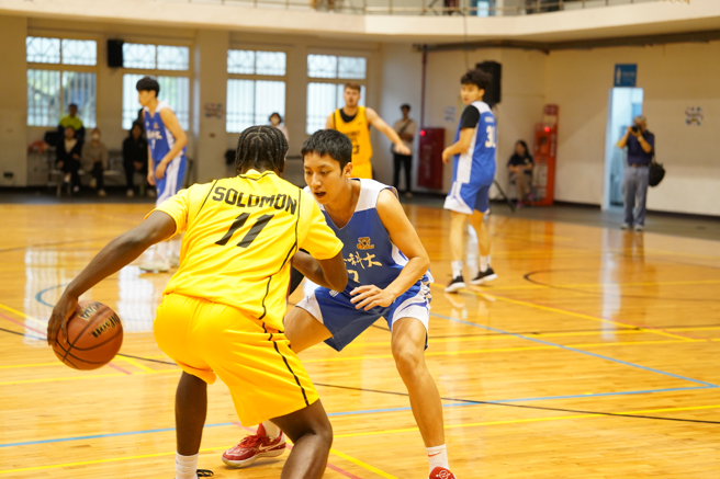 NCAA球員Solomon想運球過人，醒吾科大籃球隊長仲俊威卬足勁貼身防守。(醒吾科大提供)