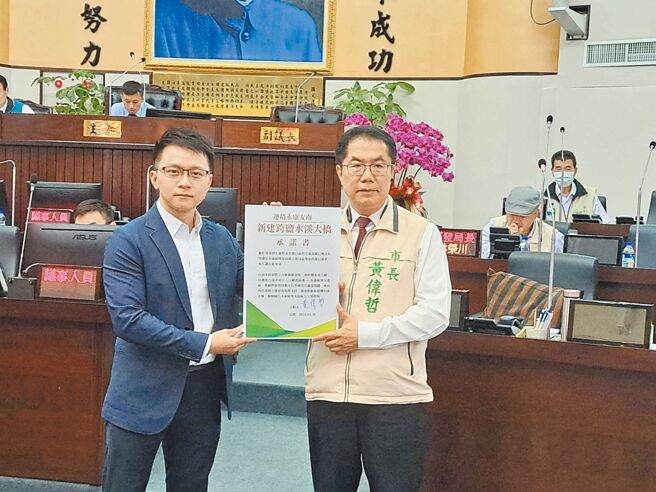 為紓解永康區與安南區的交通壓力，市議員朱正軒（左）爭取新建第3座跨鹽水溪大橋，並送上承諾書，市長黃偉哲（右）承諾會全力向中央爭取經費支持。（曹婷婷攝）