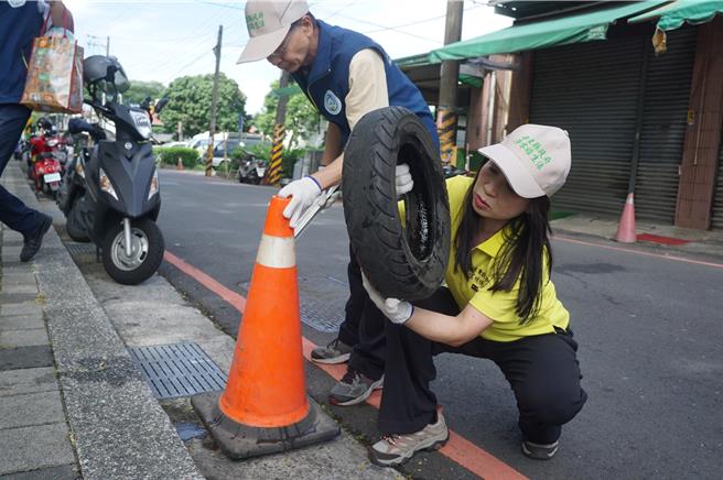屏東縣環保局長顏幸苑拿起廢輪胎，檢視裡面的積水。（羅琦文攝）