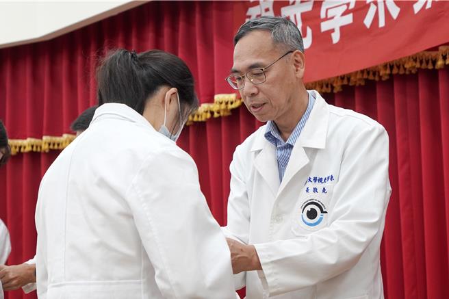 大叶大学视光系老师为学生扣上白袍的第一颗扣子，期许这些即将踏入职场的实习生，带着专业知识与师长的祝福，肩负起验光师的责任，成为优秀且专业的医事人员。（大叶大学提供／叶静美彰化传真）