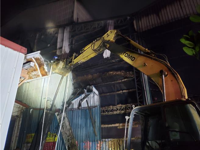 雲林縣消防局人員漏夜坐在怪手車斗撲滅殘火。（周麗蘭攝）
