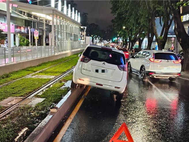 高雄一名7旬老翁下雨天開車，左轉過程差點轉進輕軌軌道，左側車輪卡在緣石動彈不得，影響列車通行約1小時，高捷公司立即啟動公車接駁旅客。（警方提供／任義宇高雄傳真）