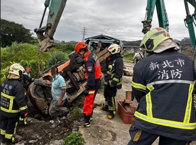工人駕駛推高機不慎翻覆，駕駛腿部遭壓住受困，消防隊到場協助脫困後送醫。（翻攝畫面）