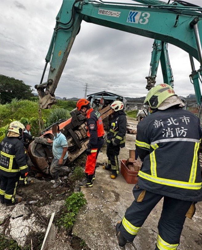 工人駕駛推高機不慎翻覆，駕駛腿部遭壓住受困，消防隊到場協助脫困後送醫。（翻攝畫面）
