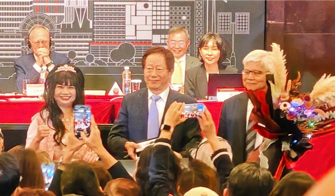 台积电股东会提问环节，有股东希望讲一段有智慧的话，刘德音趣答「买台积电」，也有股东赠花给台积电经营团队，董事长刘德音（中）、总裁魏哲家（右）代表受花。（图／柳名耕摄）