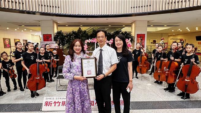 竹北市十興國小弦樂團4日在中醫大新竹附設醫院舉辦「愛的禮讚」音樂會，新竹附醫執行長張宜真（左）頒發感謝狀給十興國小校長徐發斌（中），感謝該校師生透過樂音療癒醫護、病友和家屬心靈。（羅浚濱攝）